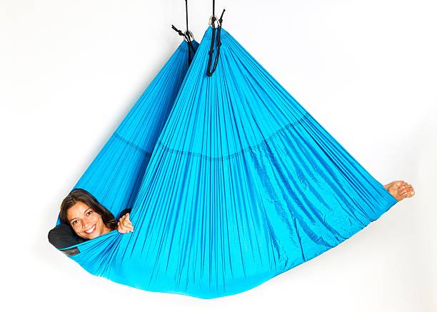 Young woman lying in hammock for anti-gravity aerial yoga stock photo