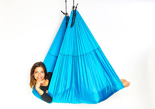 Young woman lying in hammock for anti-gravity aerial yoga stock photo