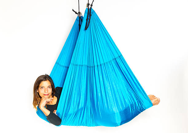Young woman lying in hammock for anti-gravity aerial yoga stock photo