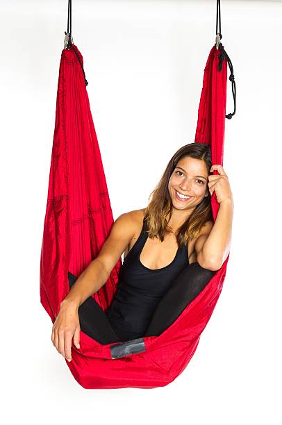 Young woman sitting in hammock for anti-gravity aerial yoga stock photo