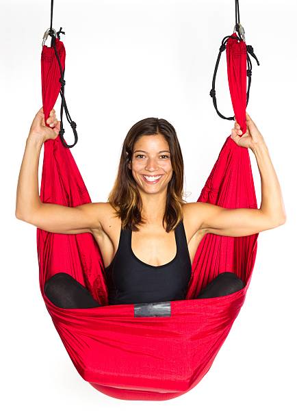 Young woman sitting in hammock for anti-gravity aerial yoga stock photo