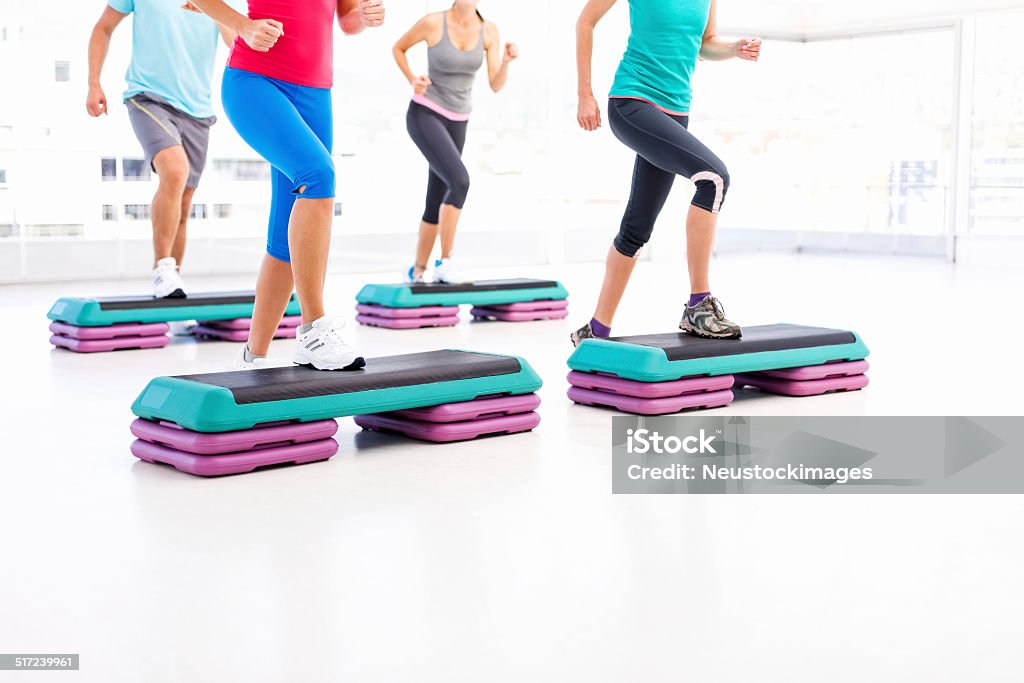 Friends Doing Aerobics Using Stair Stepper In Health Club Low section of four friends doing aerobics using stair stepper in health club. Horizontal shot. Aerobics Stock Photo