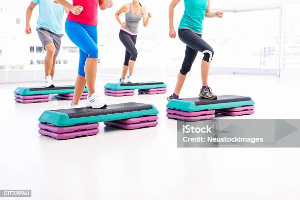 Friends Doing Aerobics Using Stair Stepper In Health Club Stock Photo - Download Image Now