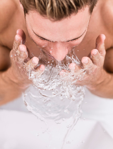 Man cleansing his face with a splash of water