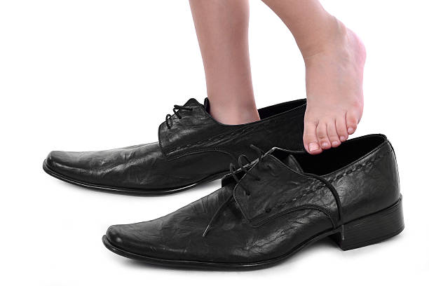 istock Little boy with big black shoes 517254495