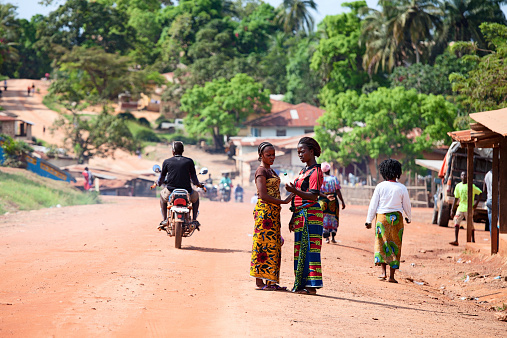 Gbarnga, Liberia - November 21, 2013: Gbarnga, Liberia - November 21, 2013: Main street in Gbarnga, Liberia. People are busy with daily activities. Two women, dressed in traditional African dress, are talking.