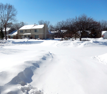 Subdivision house front yard with the street covered in snow in Rochester Hills, Michigan, for winter backgrounds 