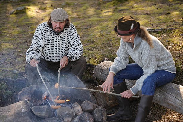 istock Senior couple grill sausages over camp fire 517267125