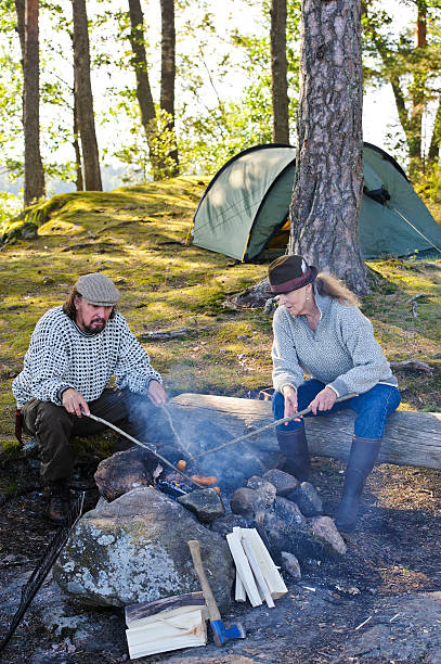 istock Senior couple grill sausages over camp fire 517267325