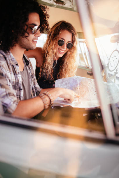 istock Hipster Couple Sitting in Van Looking at Road Trip Map 517267800
