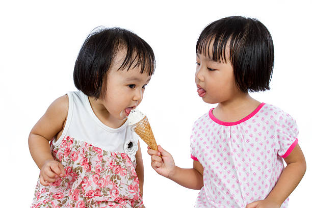 Asian Little Chinese Girls Eating Ice Cream Asian Little Chinese Girls Eating Ice Cream isolated on White Background asian little chinese girls eating ice cream stock pictures, royalty-free photos & images