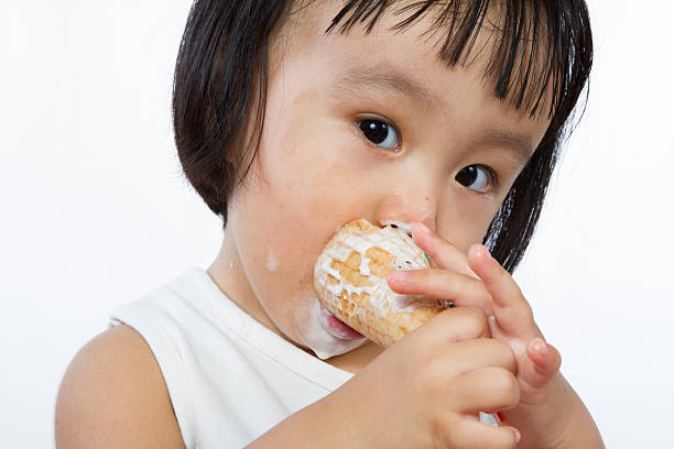 Asian Little Chinese Girl Eating Ice Cream Asian Little Chinese Girl Eating Ice Cream isolated on White Background asian little chinese girls eating ice cream stock pictures, royalty-free photos & images