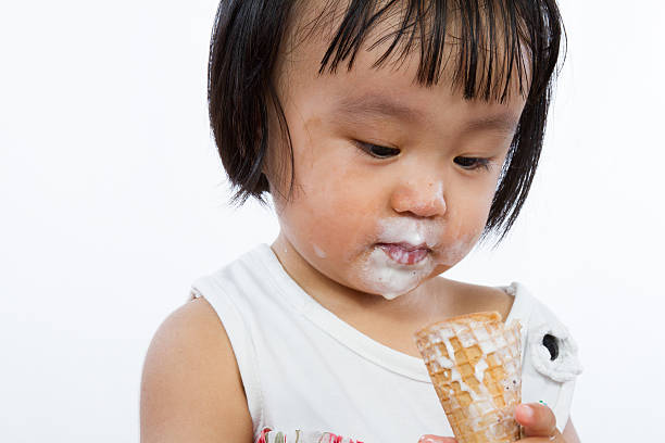 Asian Little Chinese Girl Eating Ice Cream Asian Little Chinese Girl Eating Ice Cream isolated on White Background asian little chinese girls eating ice cream stock pictures, royalty-free photos & images