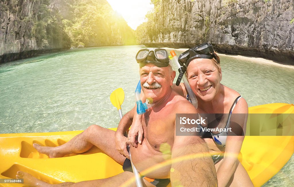 Senior couple taking selfie on kayak in El Nido lagoon Senior happy couple taking selfie on kayak at Big Lagoon in El Nido Palawan - Travel to Philippines wonders - Active elderly concept around the world - Lens flare and sun halo are part of composition Senior Adult Stock Photo