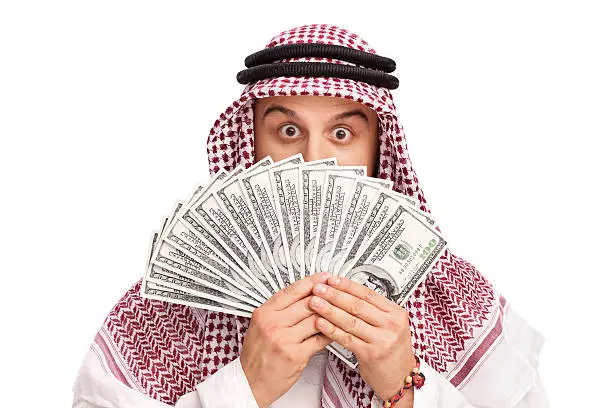 Photo of Arab hiding behind a stack of money