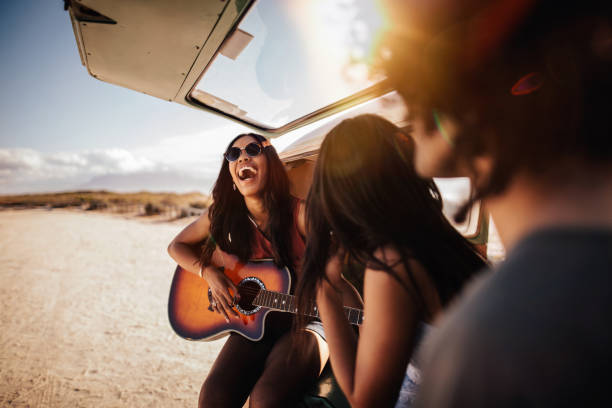 hipster grupo multiétnico tocar guitarra na praia - group of people women beach community imagens e fotografias de stock