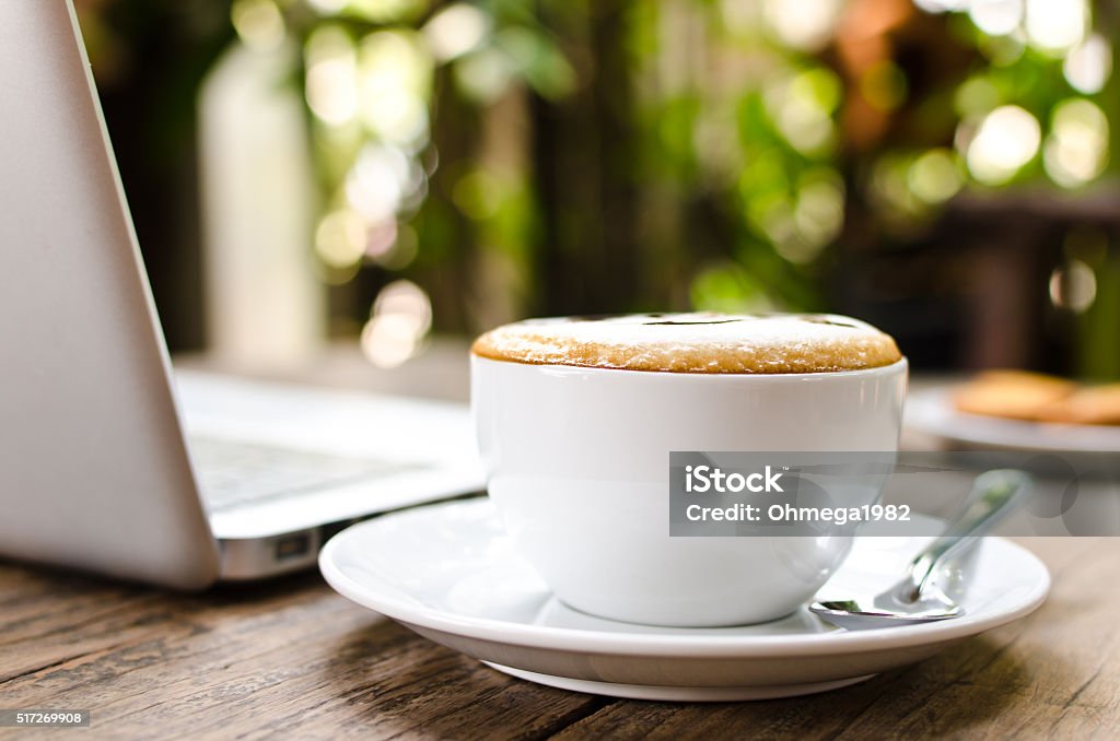 Coffee cup and laptop on the wood texture. Coffee cup and laptop on the wood texture, selective focus on coffee cream. Arranging Stock Photo