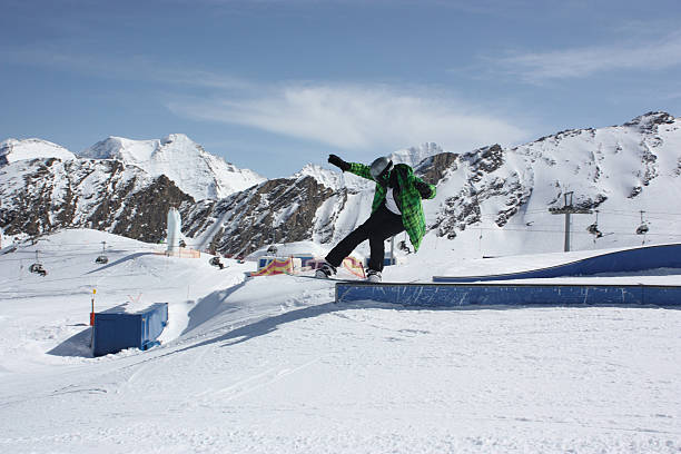 joven hombre snowboarder deslizante en una caja. - ski jumping snowboarding snowboard jumping fotografías e imágenes de stock