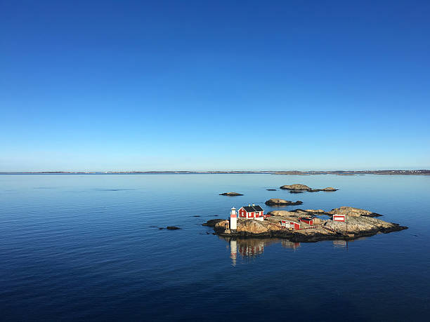 Rocky Island in a Fjord of Sweden Rocky Island in a fjord of sweden, blue sky, blue calm water, red house and small lighthouse, very calm scene lighthouse photos stock pictures, royalty-free photos & images