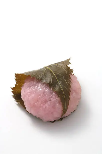 Sakuramochi, japanese confectionery wrapped in a preserved cherry  on white background.