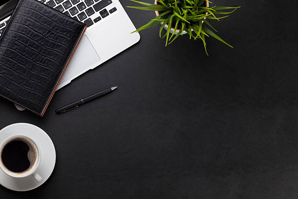 Office desk with laptop, coffee, notepad and plant