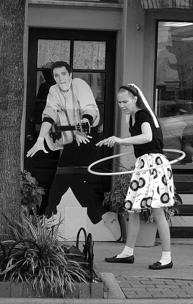 Louiseville,United States - July 18, 2010: A girl was dressed in the 60s using a Hula Hoop with a poster  image of someone resmebling  Elvis in the backgrownd. Its a black and white photo and is very  brings back Nastasic memories. The photo was taken in Louisville Kentucky.. 