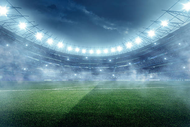 Dramatic football stadium with fog Outdoor floodlit stadium full of spectators under stormy evening sky and fog stadium stock pictures, royalty-free photos & images