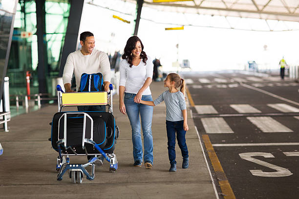 giovane famiglia in aeroporto con carrello bagagli completo - baggage wagon foto e immagini stock