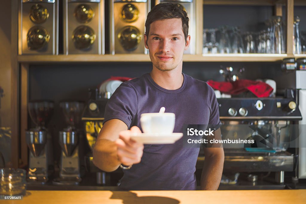 Bartender offering coffee Young man working as a bartender is offering coffee Adult Stock Photo