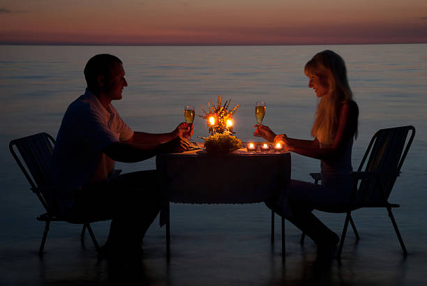 istock young couple share romantic dinner with candles on the beach 517286559
