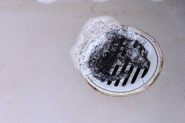 Hair clump in bath drain while taking a shower. stock photo