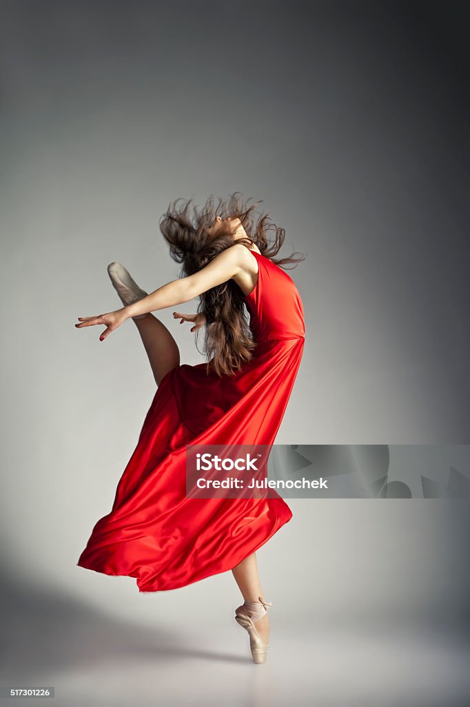 Ballet dancer wearing red dress over grey Gorgeous young ballet dancer wearing red dress over dark grey background Activity Stock Photo