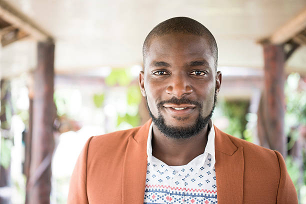 Portrait of Nigerian man with beard looking at camera Attractive young African man looking at camera. Contented young man with facial hair and moustache facing camera, Nigeria, Africa. nigeria stock pictures, royalty-free photos & images