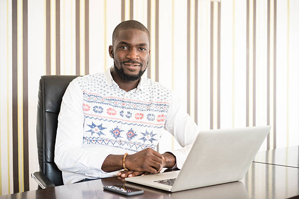 afrikanischen geschäftsmann mit laptop in moderne büro - africa business aboriginal computer stock-fotos und bilder