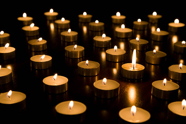 istock Single lit tealight candle surrounded by others with smaller flames 517306703