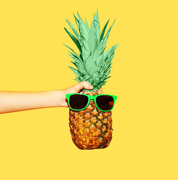 Fashion pineapple with sunglasses on yellow background, hand holding ananas Fashion pineapple with sunglasses on yellow background, hand holding ananas ananas stock pictures, royalty-free photos & images
