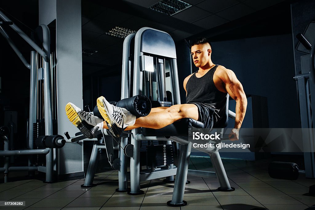 Strong young man doing legs exercise in the gym Exercise Machine Stock Photo