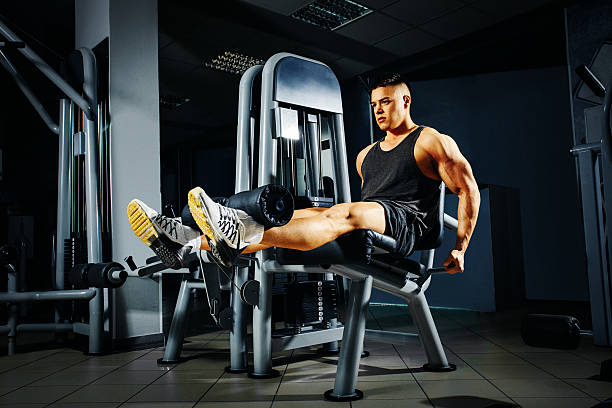 Strong young man doing legs exercise in the gym stock photo