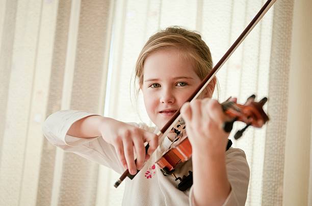 istock Smiling child playing violin at home 517308454