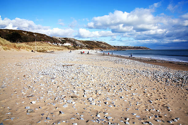 Port Eynon Bay, West Glamorgan,Wales, UK, March 5, 2016 : Holidaymakers on vacation making the most of the sun on a golden sandy beach of the Gower Peninsular