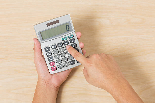 istock Hand hold and press Calculator on Wood Background 517309524