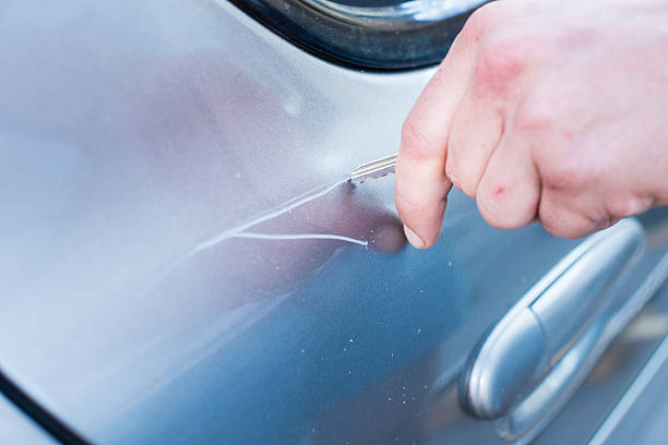 Scratching Car With A Key Man's hand scratching a car with a key.  vandalism stock pictures, royalty-free photos & images