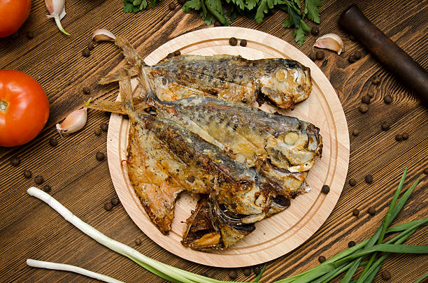 istock fried fish on a wooden board with spices 517314574