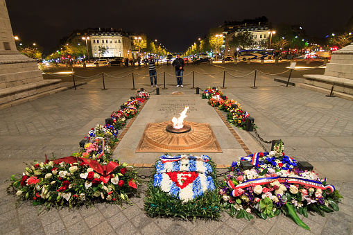 Paris, France - April 13, 2014: Tourists look at the tomb of the unknown soldier at the Arc the Triomphe at night in Paris, France, on April 13, 2014
