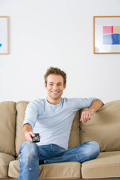 istock Young man watching television 517321257