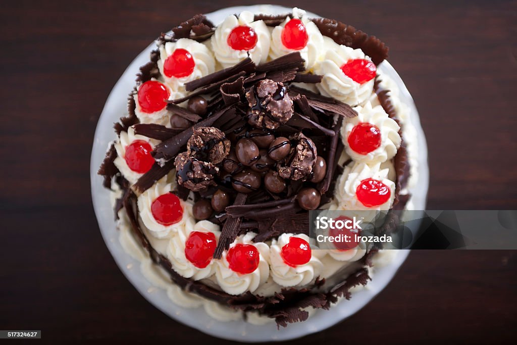 Chocolate cake with cream and cherries, from above. Delicious cake decorated with chocolates, cherries and cream. Picture taken from above. Black Color Stock Photo