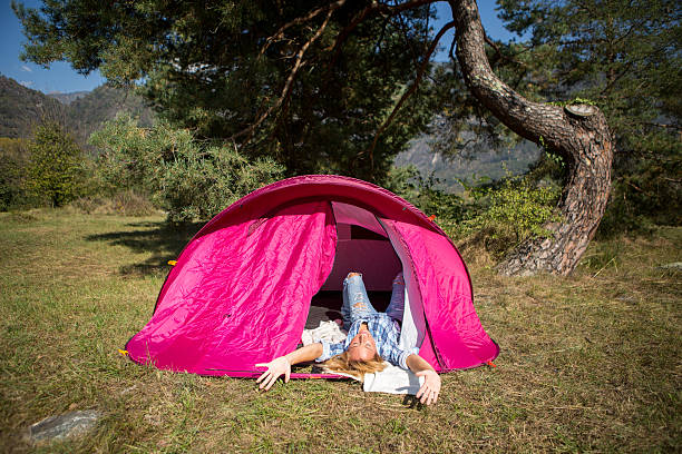 Woman laying down in tent enjoying nature Woman enjoying camping women lying down grass wood stock pictures, royalty-free photos & images