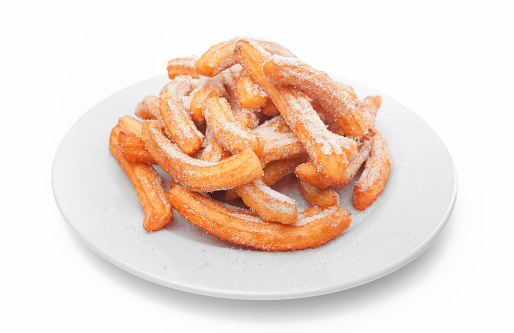 Newly made Spanish churro on white dish isolated on wihte background. Churos is typical pastry mexican breakfast dessert eaten with hot chocolate, lemon cream, sugar and cinnamon, caramel