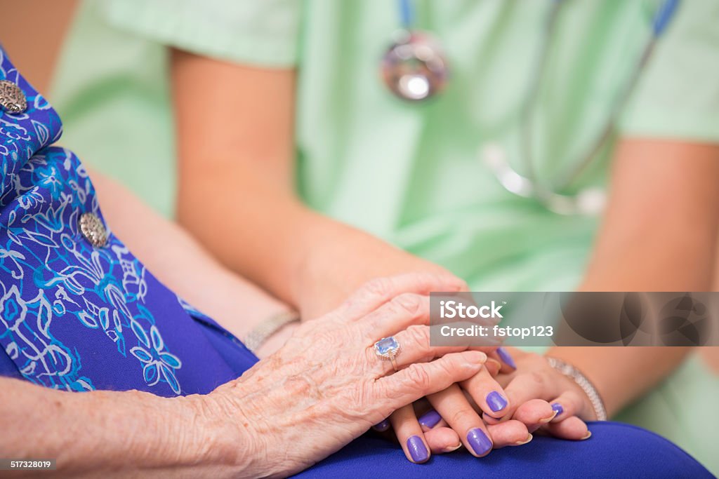 Home healthcare nurse holds senior woman's hands. Consoling. Kindness. Kind, home healthcare nurse holds elderly woman's hands.  Consoling.  Woman is over 100 years old! 20-29 Years Stock Photo