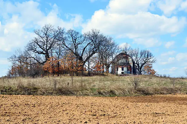 Early spring in Bulgarian countryside, ruined old Orthodox church hidden in a bare-tree grove